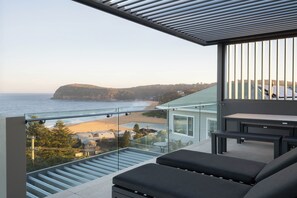 A balcony with a glass railing overlooking a beach and ocean. - “Oceanview & Seabreeze” - with Pool (Copacabana)