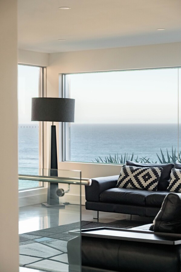 Un salon moderne avec un canapé, une lampe sur pied et une vue sur l’océan.