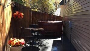 Eine Holzterrasse mit Whirlpool, Tisch und Stühlen.