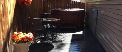 Una terraza de madera con un jacuzzi, una mesa y sillas.