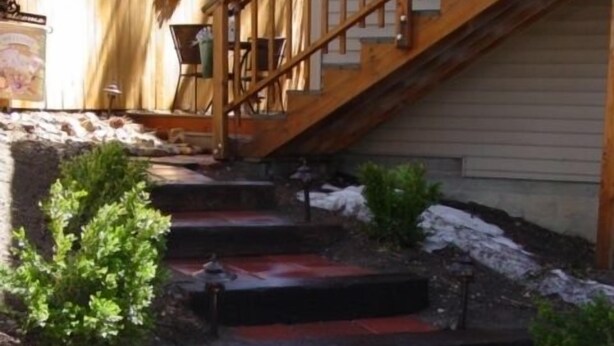 Eine Holztreppe führt zu einem Haus, versehen mit einem Holengeländer.