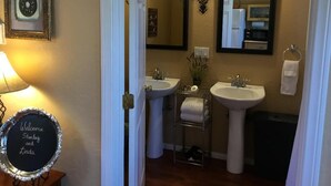 Ein Badezimmer mit zwei Waschbecken, einem Spiegel, einem Handtuchhalter und einem Willkommensschild.
