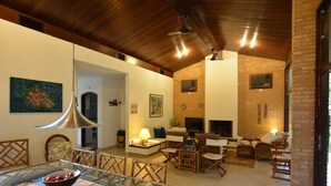 Amplia sala de estar con chimenea, asientos cómodos y comedor con mesa de vidrio.