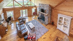 A log cabin interior with a fireplace, leather sofa, and a stone accent wall.