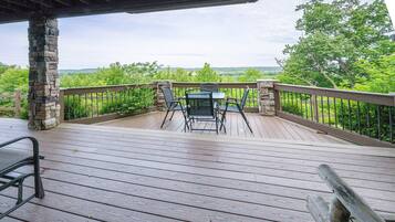A wooden deck with stone pillars, a table, and two chairs.