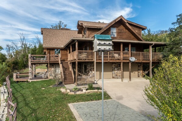 A two-story log cabin with a balcony, stone foundation, and a satellite dish. - Riverview Log Cabin Lodge Near Creation Museum & Arc Encounter (Union)