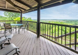 A covered outdoor deck with a table and chairs, overlooking a green landscape. - Riverview Log Cabin Lodge Near Creation Museum & Arc Encounter (Union)