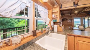A kitchen with a granite countertop, white sink, and wooden cabinets.