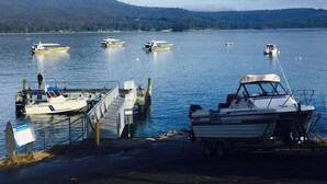 A marina with several boats docked, a wooden pier, and a mountainous backdrop. - Bayview Bruny Island Beach House (Adventure Bay)