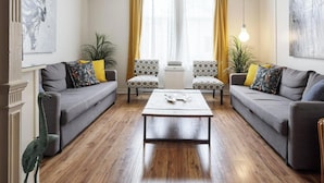 A modern living room with two grey sofas, a central coffee table, patterned armchairs, and a potted plant. - MTLVR #11 | Central, Group Friendly, Patio (Montreal)
