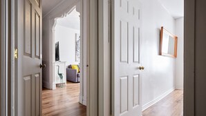 A hallway with white doors, a wooden floor, and a mirror on the wall. - MTLVR #11 | Central, Group Friendly, Patio (Montreal)