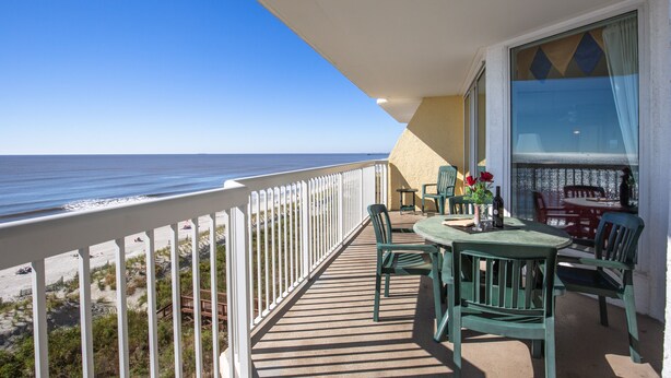 A balcony with a view of the beach and ocean.