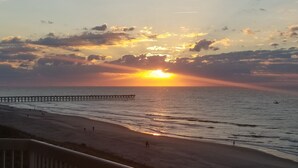 A sunset over the ocean with a pier extending into the water.