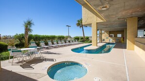 A pool area with lounge chairs and a hot tub.