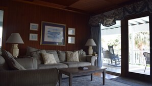 A living room with a sofa, two lamps, a coffee table, and a large framed picture on the wall. - A traditional beach house located near historic downtown Charleston (Isle of Palms)