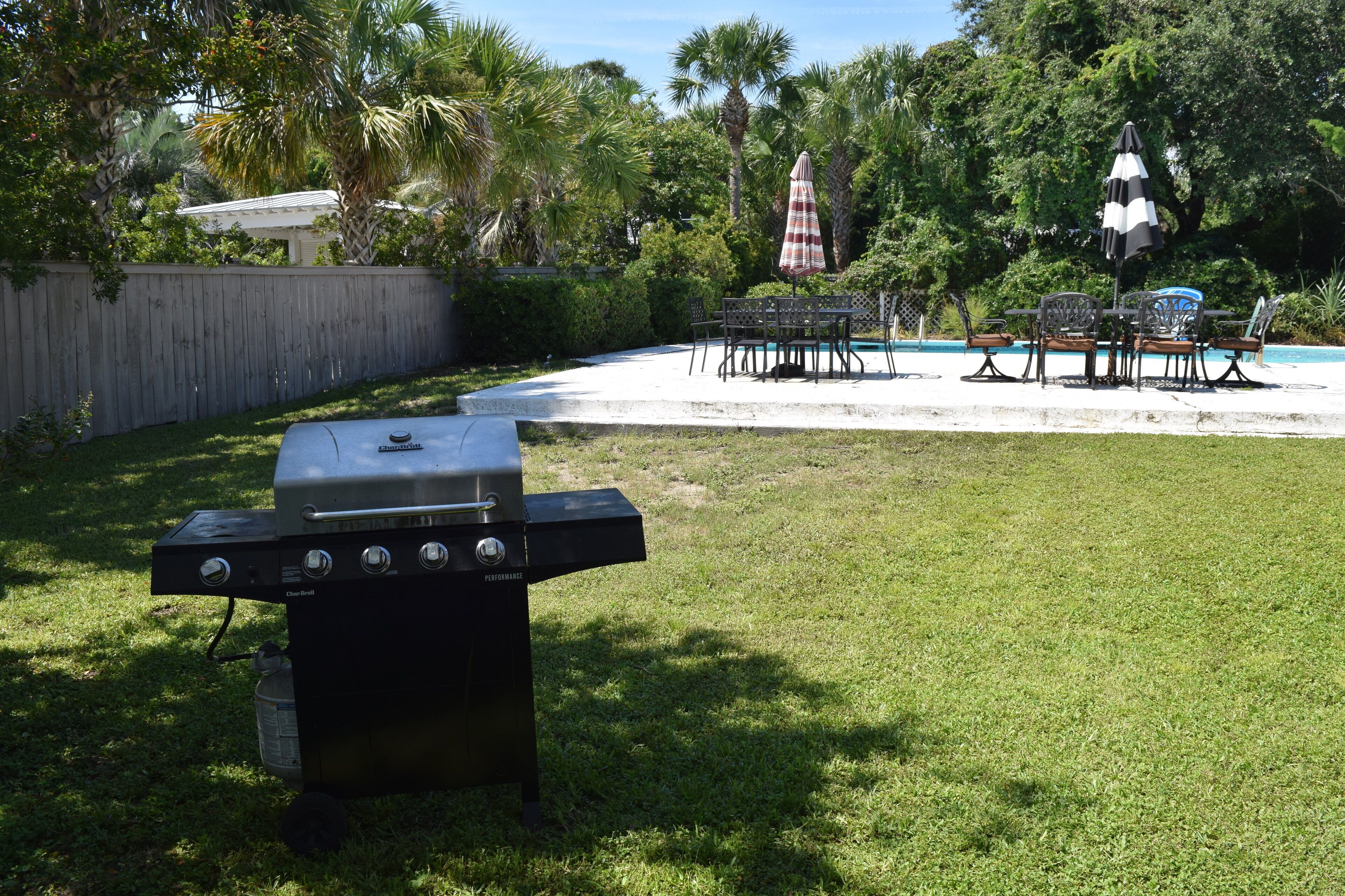 Ein Garten mit Grill, Pool und Gartenmöbeln.