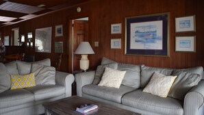 A room with two striped sofas, a coffee table, and framed artwork on the walls. - A traditional beach house located near historic downtown Charleston (Isle of Palms)