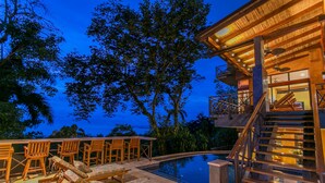 Un espace aménagé au bord de la piscine, avec des chaises longues et un escalier menant à un niveau supérieur.