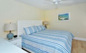 A bedroom with a bed, two bedside tables, a ceiling fan, and a painting on the wall. - Firethorn 322-Beachfront 2BR/1.5BA condo on gorgeous Siesta key (Siesta Key)