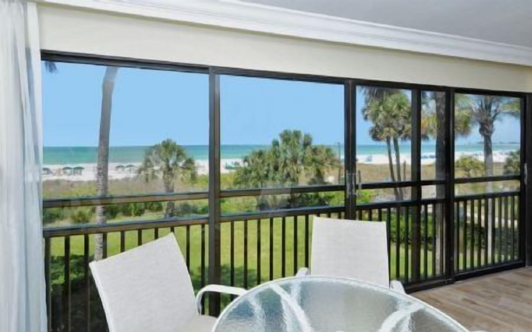 Ein Balkon mit Blick auf den Strand, einem Tisch und zwei Stühlen.
