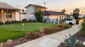 A residential area with a well-maintained lawn, a golf cart, and a white car parked on the street. - Tranquil Hip Indoor/Oudoor Living. Just Blocks from Sand. (Oceanside)