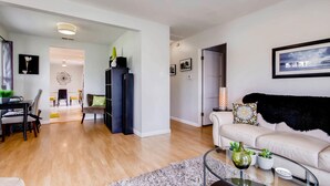 A modern living room with a sofa, coffee table, and a dining area with chairs and a table. - Tranquil Hip Indoor/Oudoor Living. Just Blocks from Sand. (Oceanside)