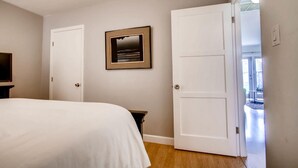A bedroom with a bed, a television, a mirror, and a door leading to a balcony. - Tranquil Hip Indoor/Oudoor Living. Just Blocks from Sand. (Oceanside)