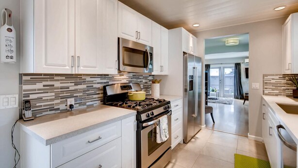 A modern kitchen with white cabinets, a stainless steel microwave, a gas stove, and a built-in oven. - Tranquil Hip Indoor/Oudoor Living. Just Blocks from Sand. (Oceanside)