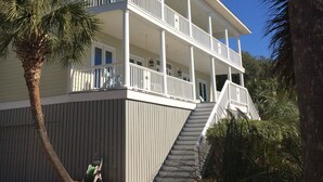 Ein zweistöckiges Gebäude mit einem Balkon, einer Treppe, die zum oberen Stockwerk führt, und einer Palme im Vordergrund.
