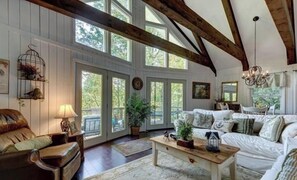 Ein geräumiges Wohnzimmer mit großem Fenster, Holzboden und weißem Sofa.