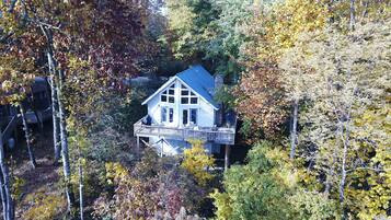Ein Haus, umgeben von Herbstlaub, mit einer Terrasse und mehreren Fenstern.