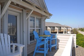 A covered outdoor area with a wooden deck, a table, and two chairs. - Gone Coastal - 2nd Row home; 4BR; Ocean Views from Sun Deck (Surf City)
