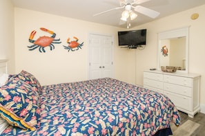 A bedroom with a bed, a dresser, a television mounted on the wall, and a ceiling fan. - Gone Coastal - 2nd Row home; 4BR; Ocean Views from Sun Deck (Surf City)