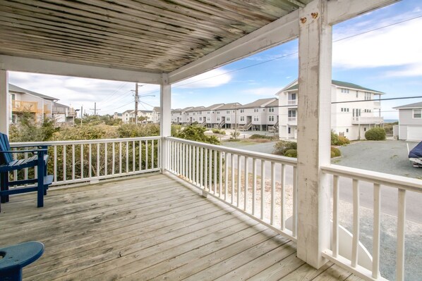 A covered porch with a view of a residential area, featuring a wooden floor and white railings. - Gone Coastal - 2nd Row home; 4BR; Ocean Views from Sun Deck (Surf City)