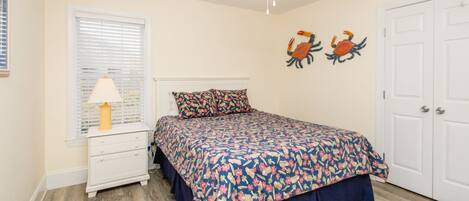 A bedroom with a bed, a nightstand, a lamp, a ceiling fan, and two wall art pieces.
