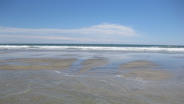 Ein Strand mit klarem Wasser und einer sichtbaren Sandbank.