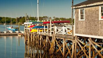 A wooden pier with a small building at the end, boats docked along the pier, and calm water reflecting the structure.