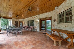 Relax in this charming outdoor space with a wooden ceiling fan, stone walls, and a picnic table.