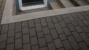 A blue door with a small window, a keypad, and a set of concrete steps leading up to a door.