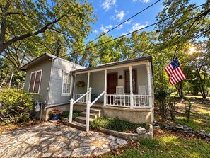 A two-story house with a porch, a front yard, and an American flag.