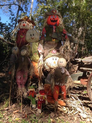 A collection of scarecrow figures made from straw and fabric, positioned outdoors with trees in the background. - Old Country Charm 2 1/2 blocks from Main St Shopping/Private Get-a-Way w/Hot Tub (Fredericksburg)