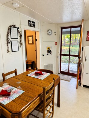 A dining area with a wooden table, chairs, and a door leading outside.