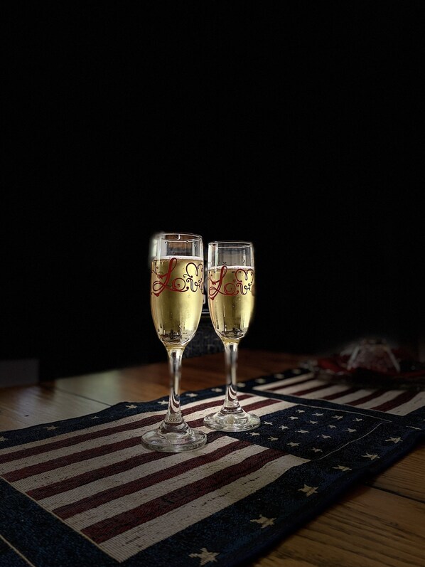 Two champagne flutes with "Love" engraved on them, placed on a table with an American flag rug. - Old Country Charm 2 1/2 blocks from Main St Shopping/Private Get-a-Way w/Hot Tub (Fredericksburg)