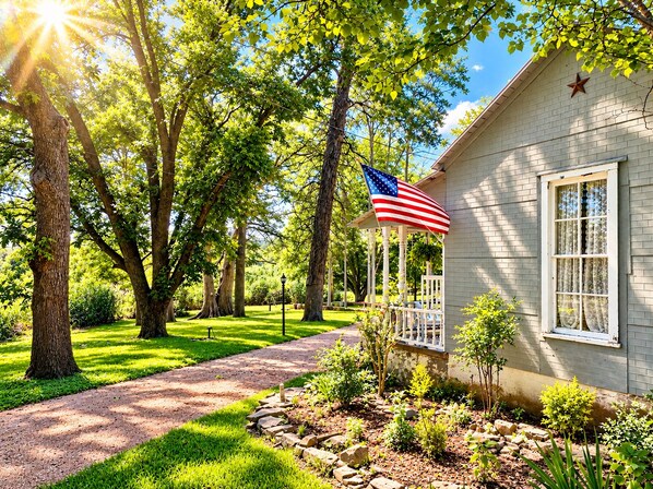 A house with a porch, a flag, and a garden.