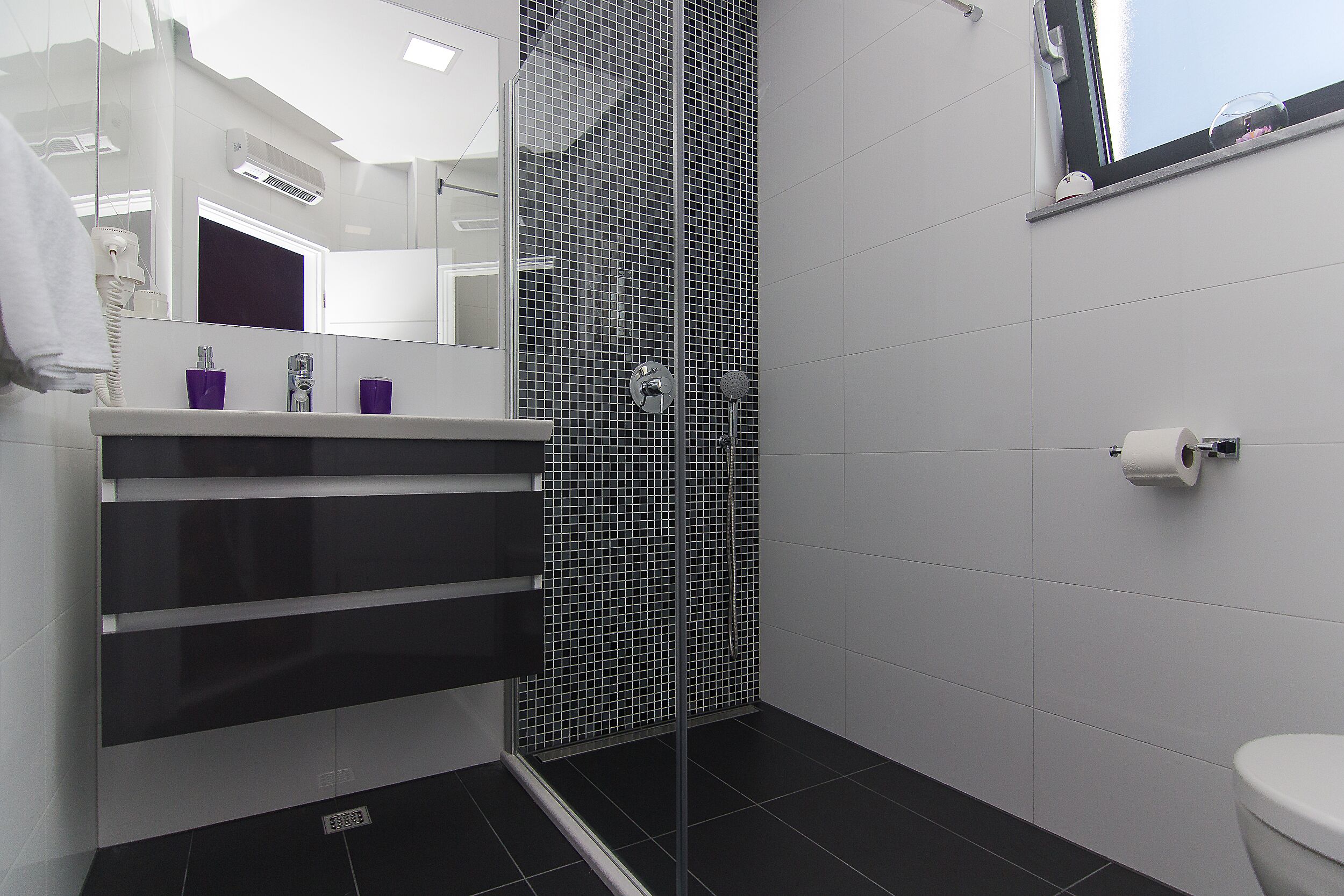 A modern bathroom with a shower, a toilet, and a sink with a mirror.