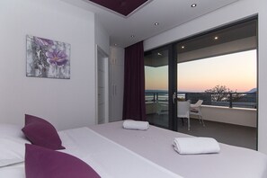 A modern hotel room with a large bed, a view of the sunset, and a balcony with a table and chairs. - Villa Marion,beheizter Pool, , %% 16,09-29,09 %% (Baška Voda)