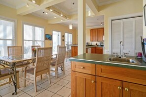 A spacious kitchen with wooden cabinets, a green countertop, and a dining area with wicker chairs.
