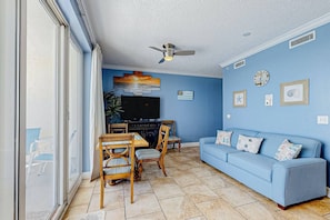 A living room with a blue sofa, wooden chairs, a television, and a ceiling fan. -  Great place to find your lost shaker of salt!BOOK EARLY FOR SPRING AND SUMMER
 (Panama City Beach)