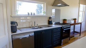 A modern kitchen with a dishwasher, sink, stove, and cabinets.