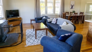 A living room with a sofa set, a coffee table, a TV, and a dining area with chairs and a table.